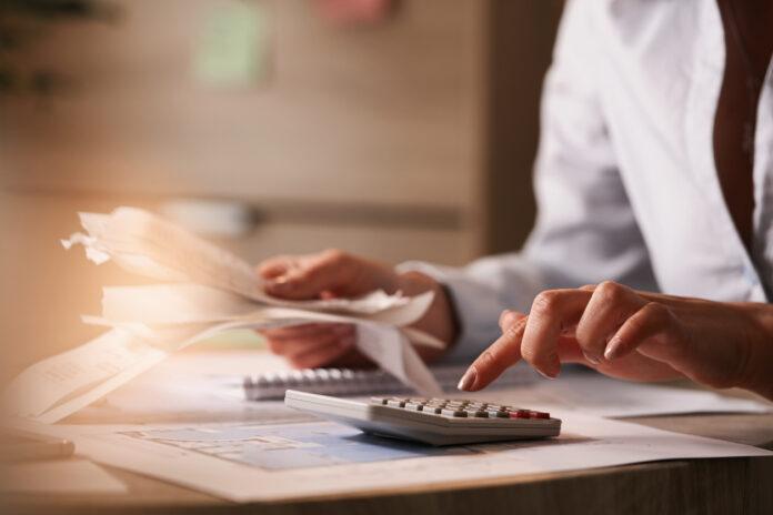 Close up of businesswoman using calculator while going through financial bills. Endividamento pessoal - a Lei admite que o devedor possa pedir a insolvência com a apresentação de um plano de pagamentos.